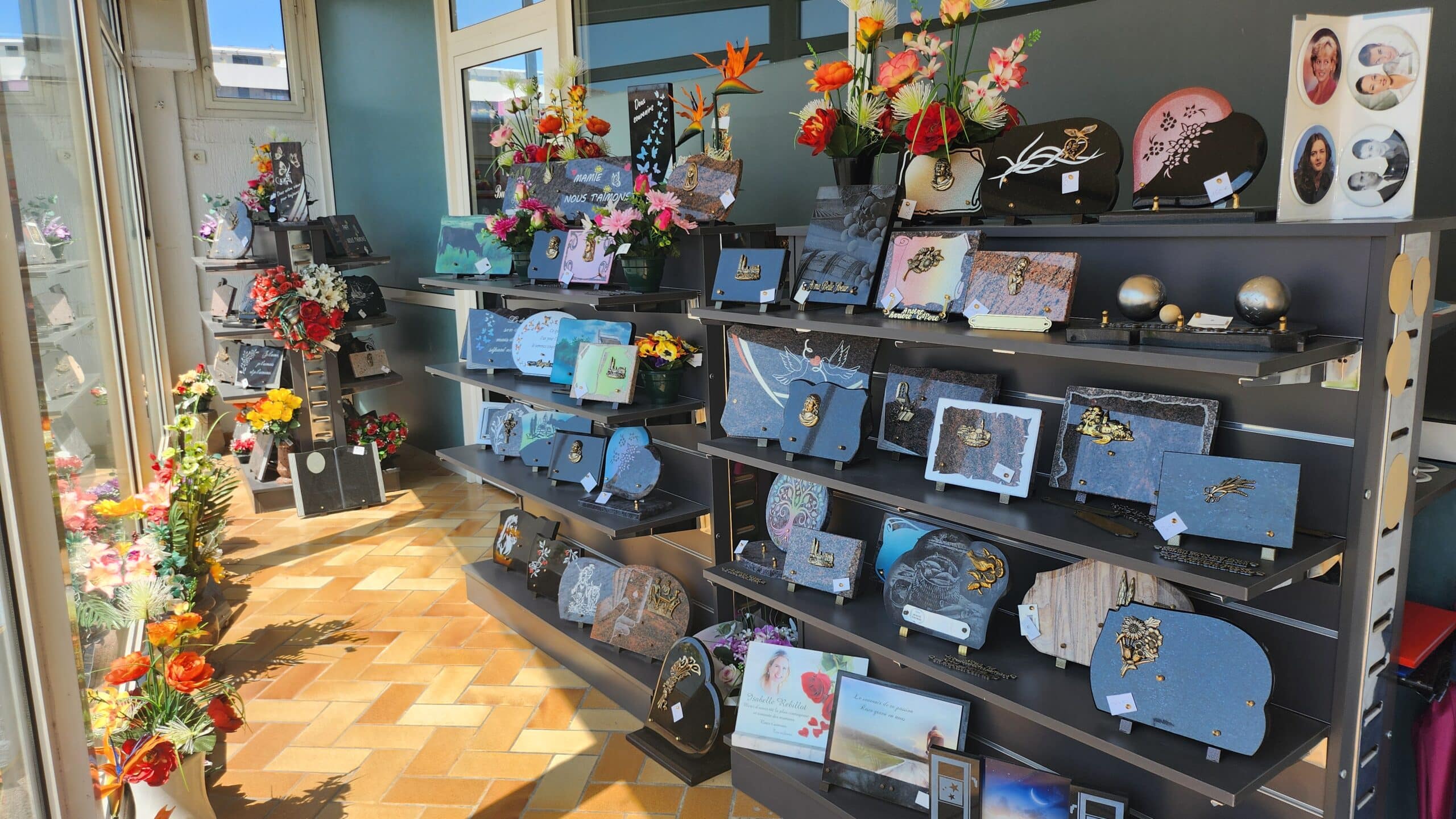 Présentation de plaques funéraires à Palavas-les-Flots, ornements et fleurs artificielles en hommage aux défunts